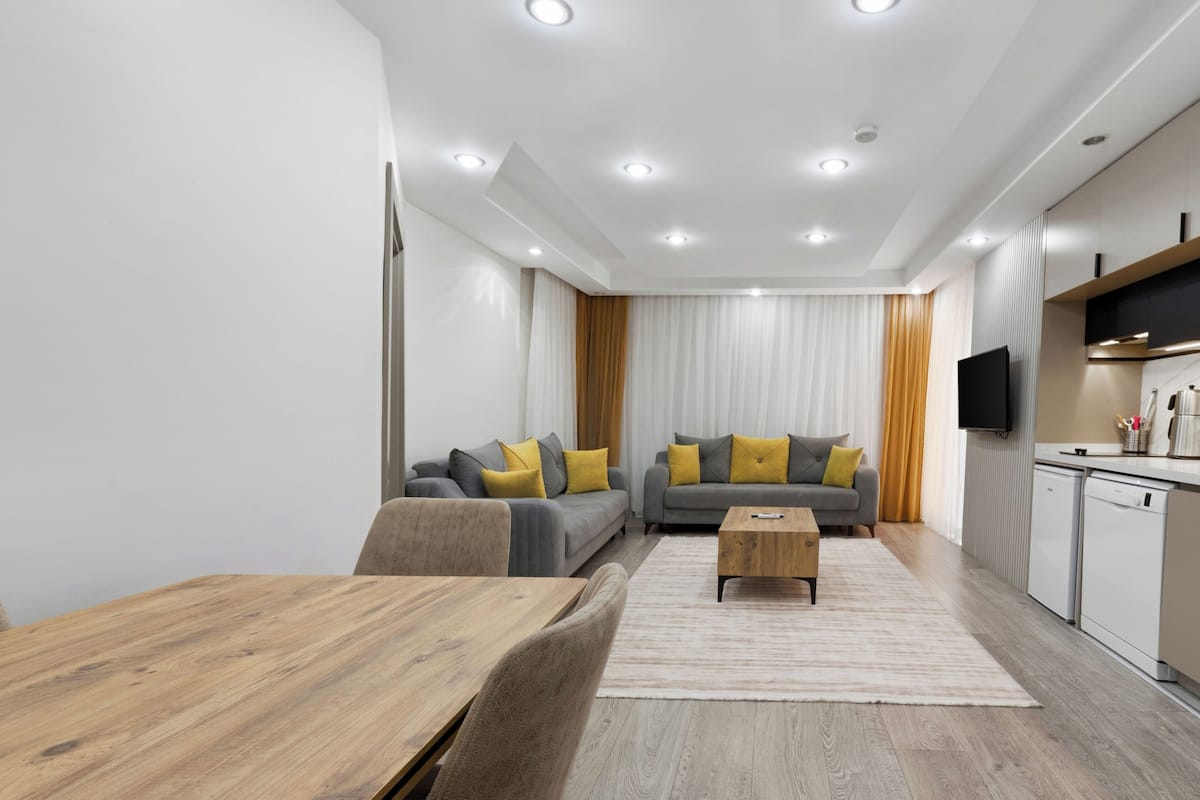 A modern living room with a sofa set, a wooden coffee table, and a dining table.