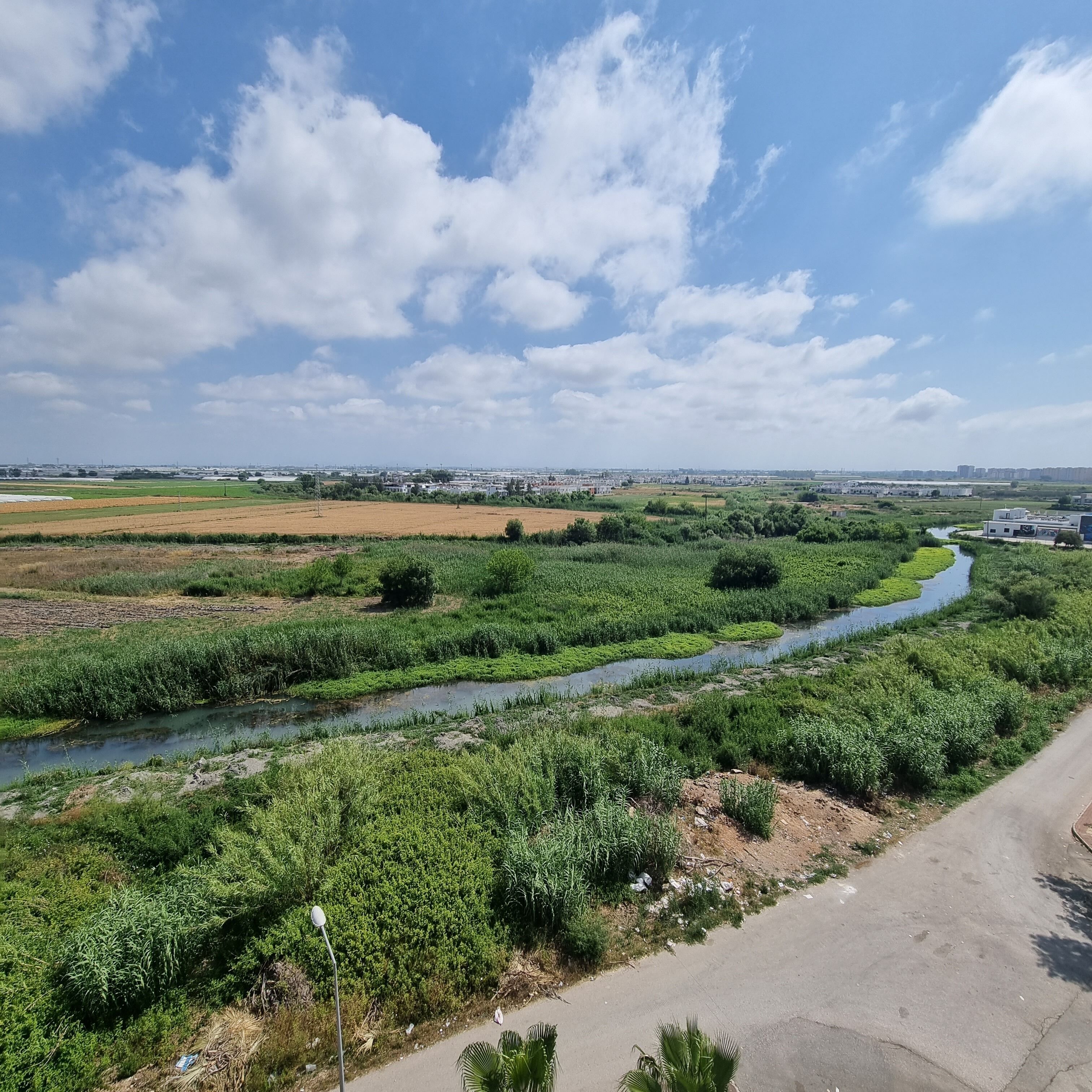 Ein Fluss schlängelt sich durch eine grüne Landschaft unter blauem Himmel.