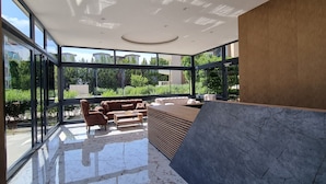 A modern interior with a glass wall, a sectional sofa, and a wooden coffee table. - River Park Residence Lara (Antalya)