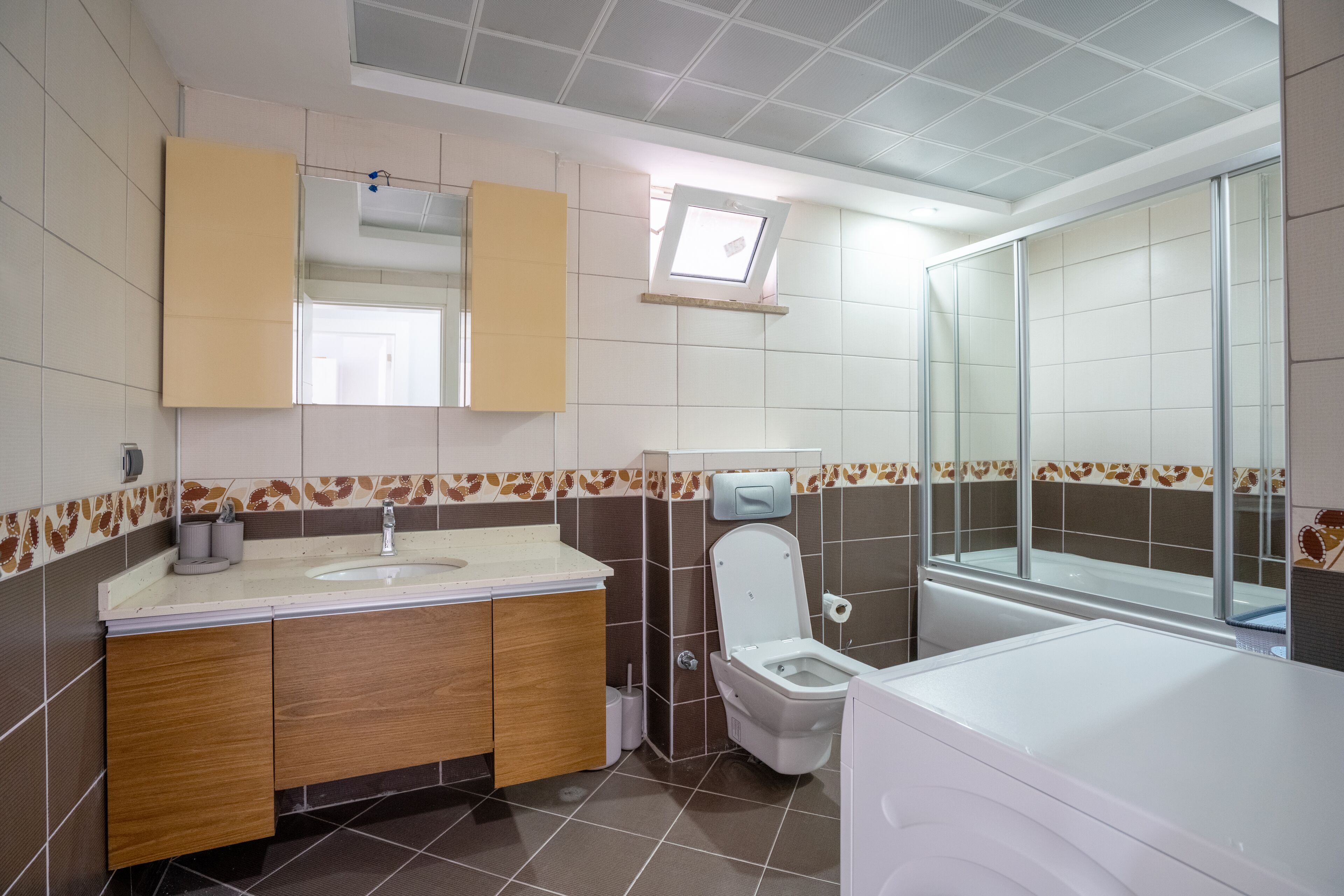 A modern bathroom with a sink, mirror, toilet, and shower area.