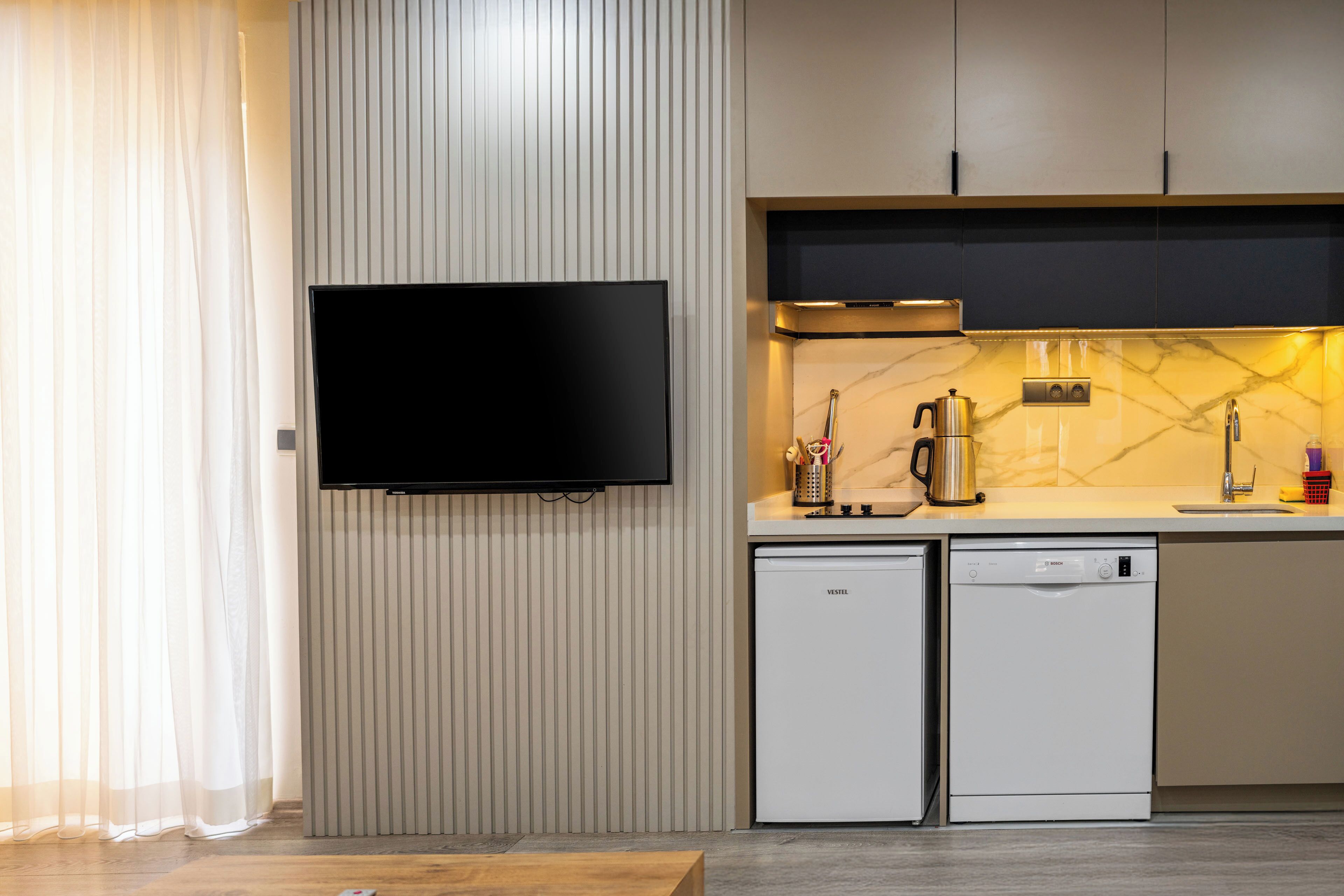 A modern kitchen with a flat-screen TV, a coffee maker, and two dishwashers.