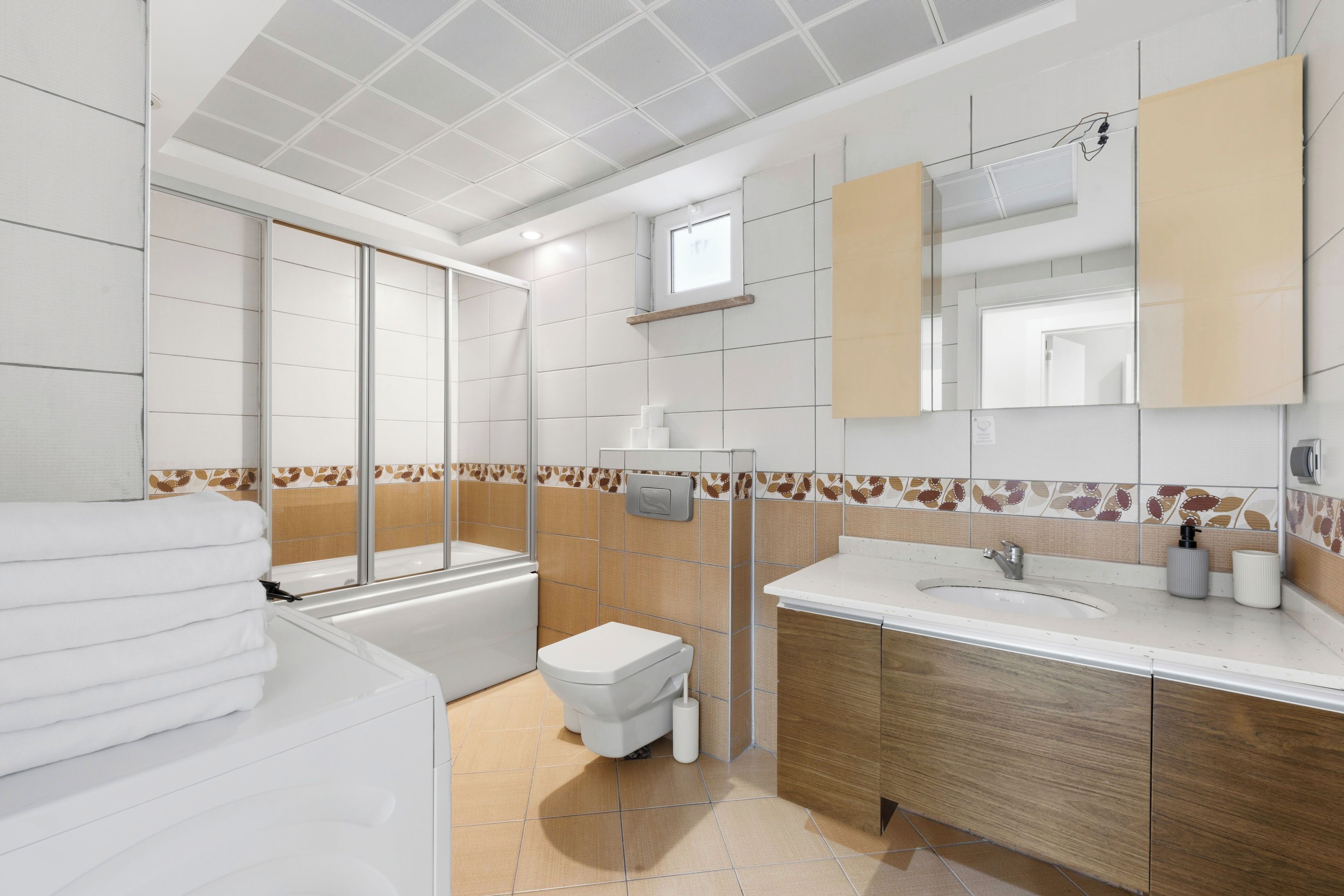 A modern bathroom with a bathtub, toilet, sink, and large mirror.