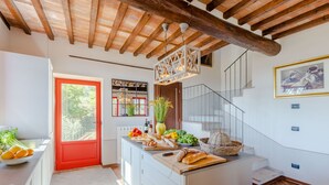 Eine Küche mit roter Tür, Holzboden und einer Treppe, die zu einer oberen Ebene führt.