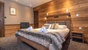 Un dormitorio con paneles de madera, una cama grande, dos mesitas de noche y un cuadro en la pared.