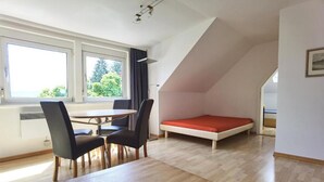 A room with a dining table, chairs, a bed, and a window. - Villa Gerster (Wasserburg am Bodensee)
