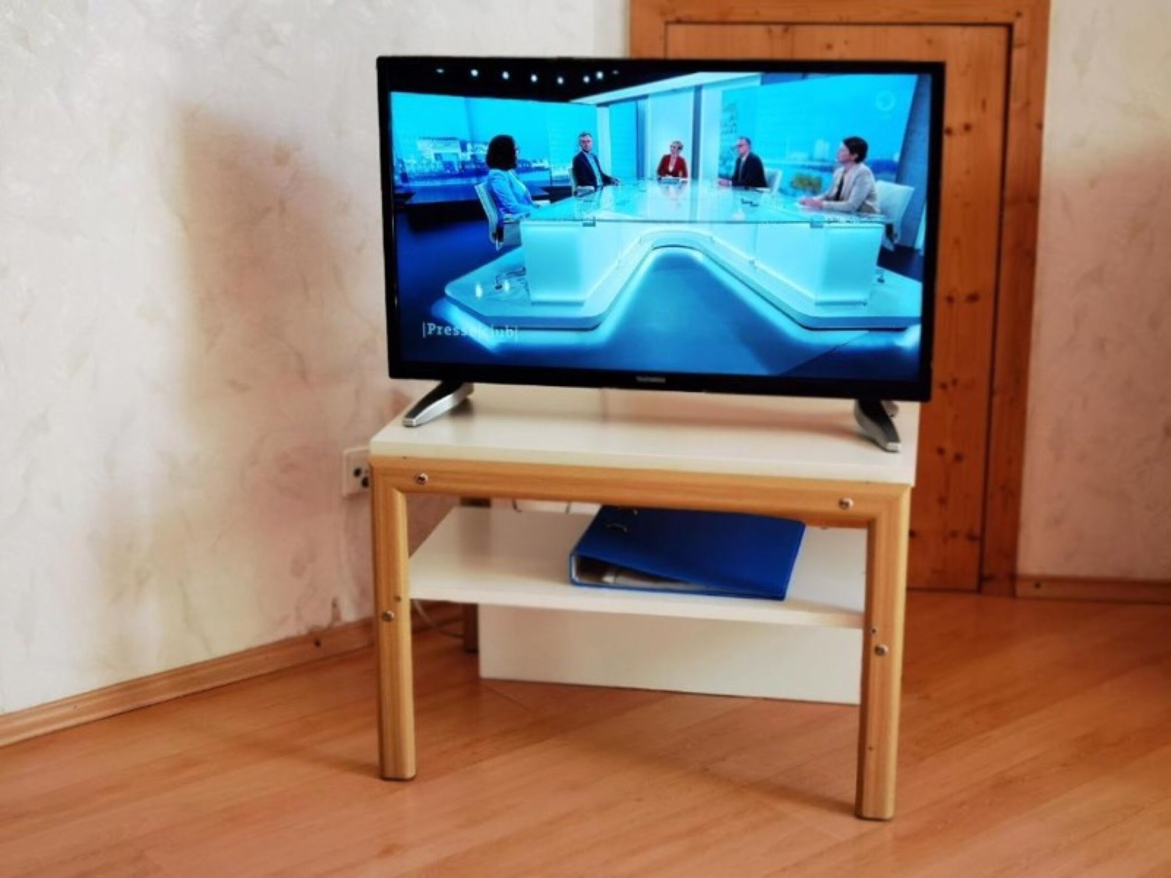 A television on a wooden stand with a flat-screen display.