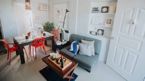 Ein modernes Wohnzimmer mit Essbereich, ausgestattet mit einer Couch, roten Sesseln, einem Couchtisch und einem Esstisch für vier Personen.
