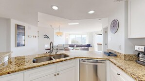 A modern kitchen with granite countertops, white cabinets, and a dishwasher. - Fifth Floor Villamare unit with lots of updates! (Hilton Head)