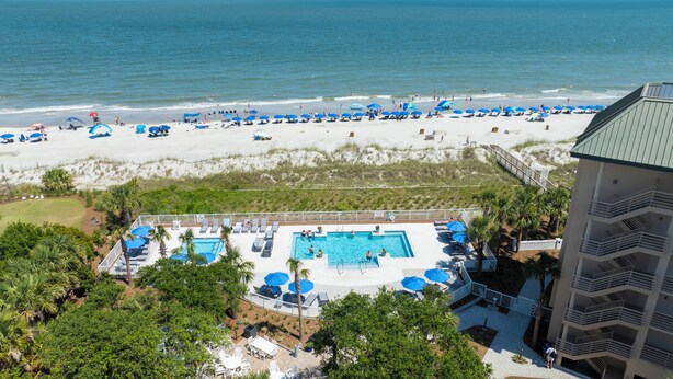 A resort with a pool area, beach access, and a building with balconies. - Fifth Floor Villamare unit with lots of updates! (Hilton Head)