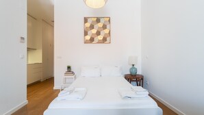 A hotel room with a large bed, a bedside table with a lamp, and a wall-mounted artwork.
