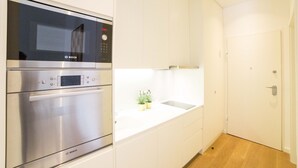 A modern kitchen with stainless steel appliances, a white countertop, and a small potted plant.