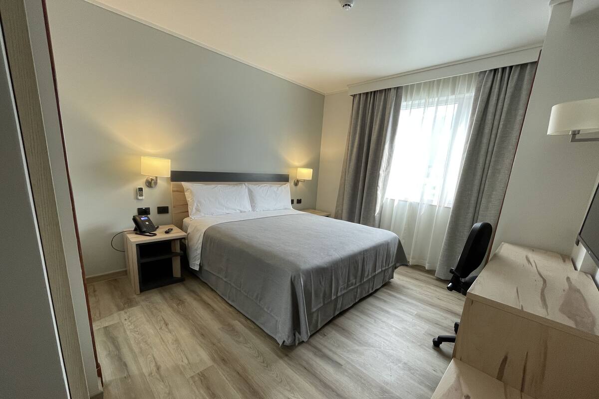 Een hotelkamer met een bed, nachtkastjes, een bureau, een stoel en een televisie.