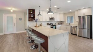 A modern kitchen with a marble island, stainless steel appliances, and pendant lighting. - Pool home,Pet friendly, 5 mins drive to Siesta Key (Sarasota)