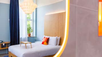 A modern bedroom with a wooden bed, a bedside table, a potted plant, and a window with curtains.