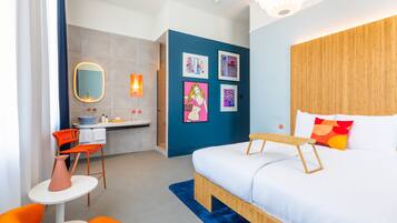 Habitació d'hotel moderna amb llit, escriptori i bany.