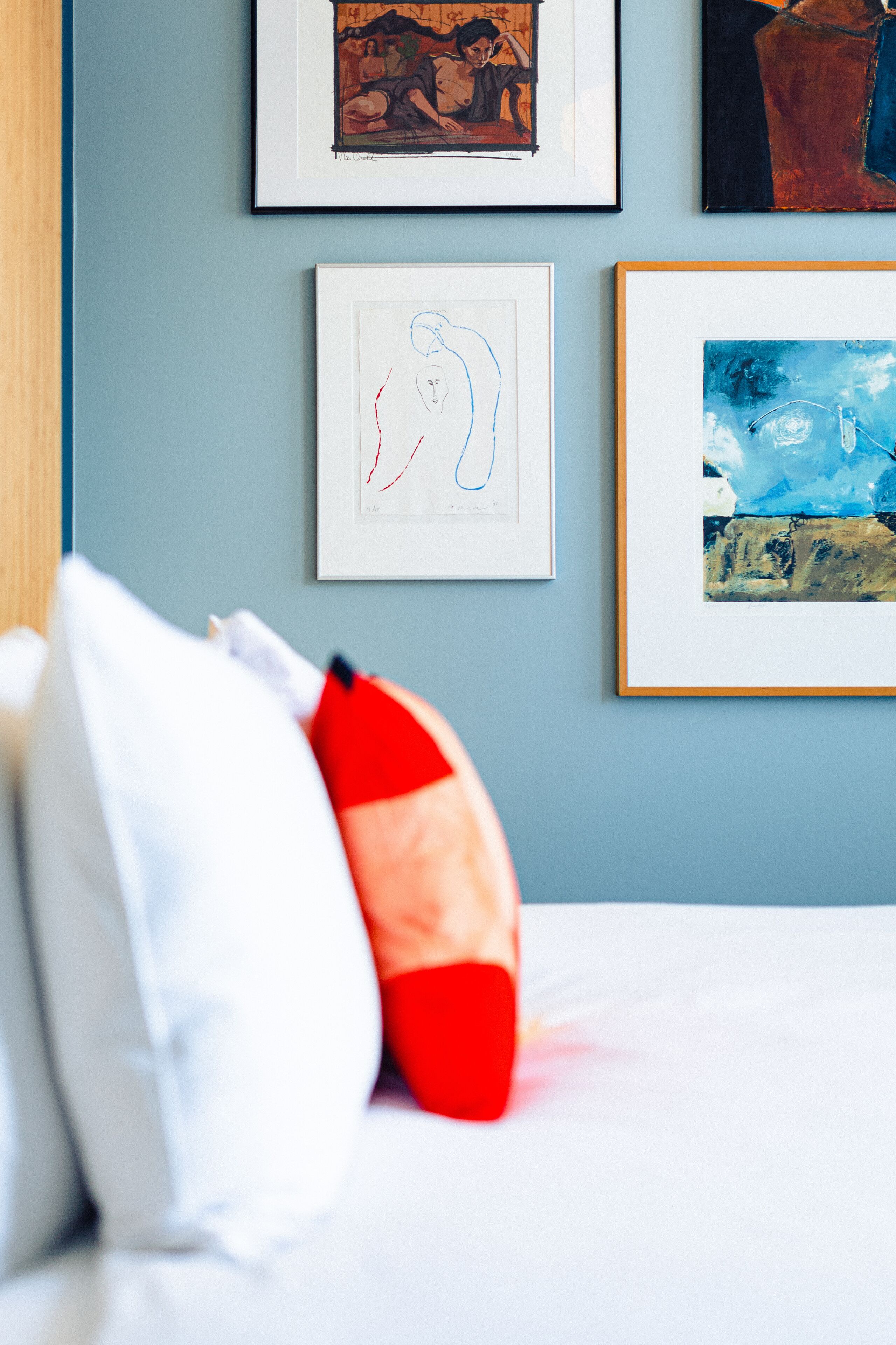 Une chambre d’hôtel avec un lit, des oreillers et des œuvres d’art encadrées accrochées au mur.