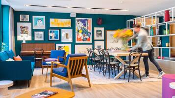 Un interior moderno con paredes verde azulado, muebles de madera y una variedad de obras de arte enmarcadas.