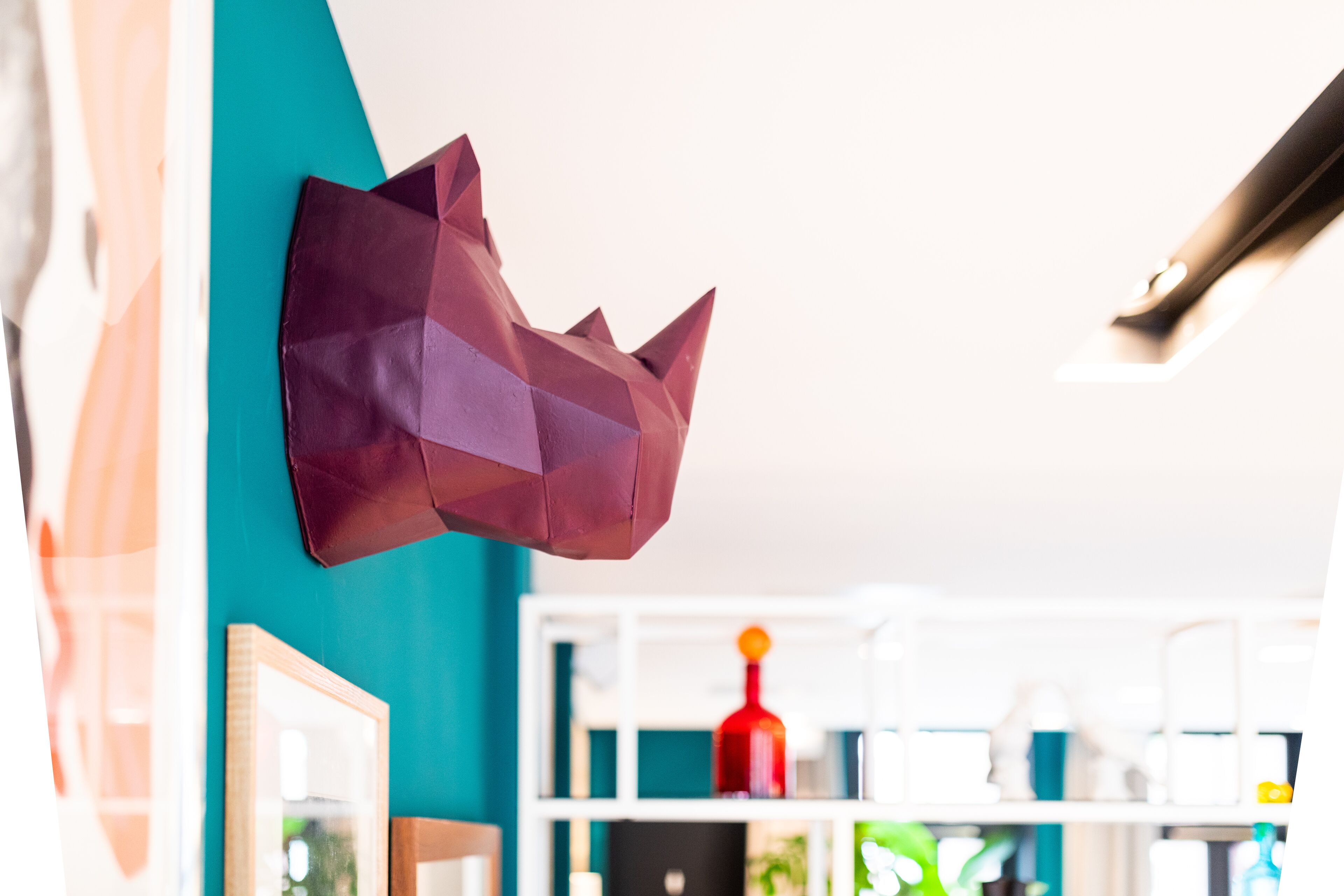 Una habitación con paredes color turquesa, una decoración con forma de corona y un estante blanco con diversos objetos.
