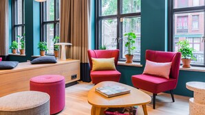Una habitación moderna con ventanas amplias, sillas rojas, una mesa de madera y plantas en macetas.
