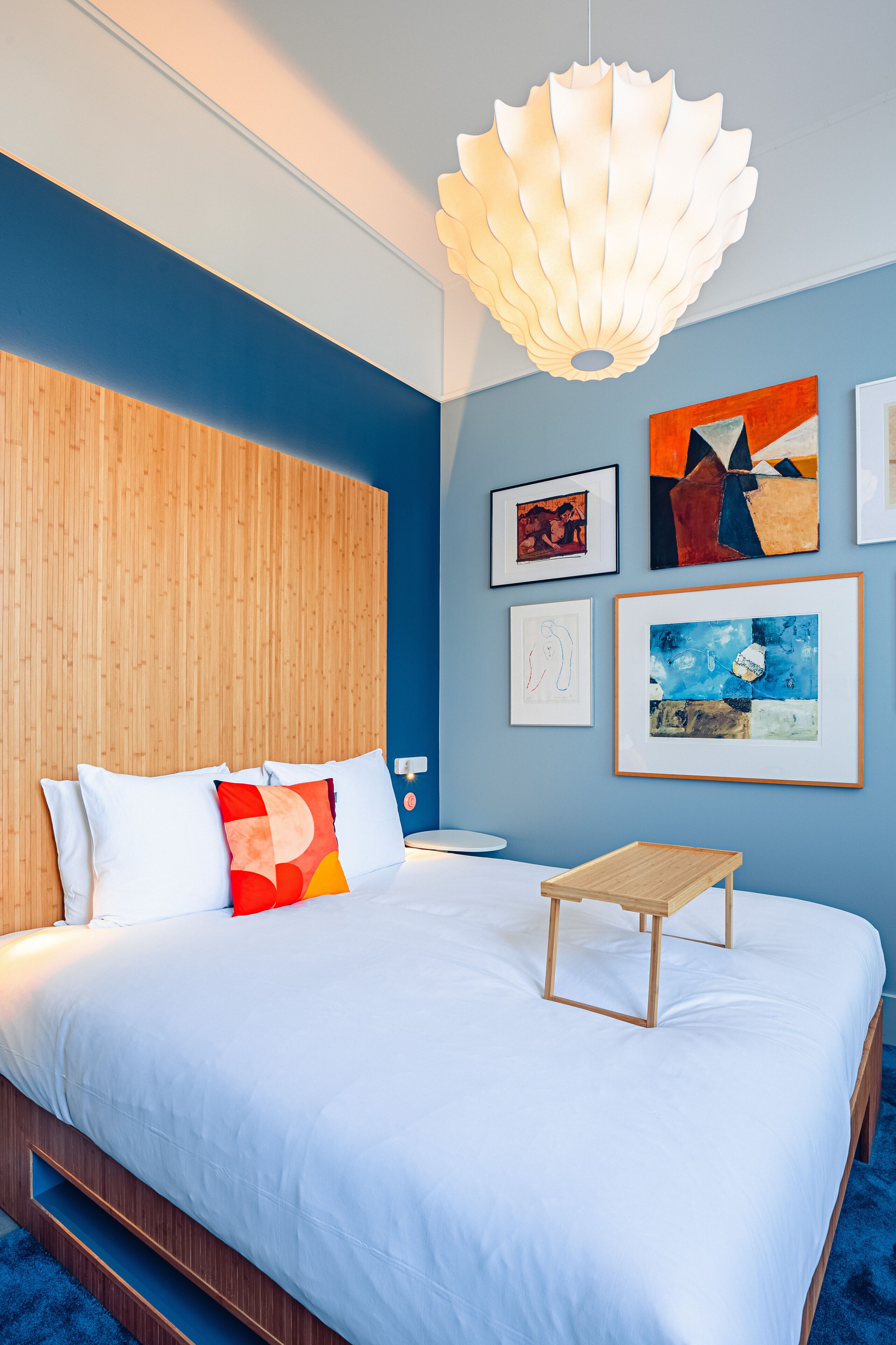 Un dormitorio moderno con una cama grande, cabecera de madera y una lámpara de techo original.