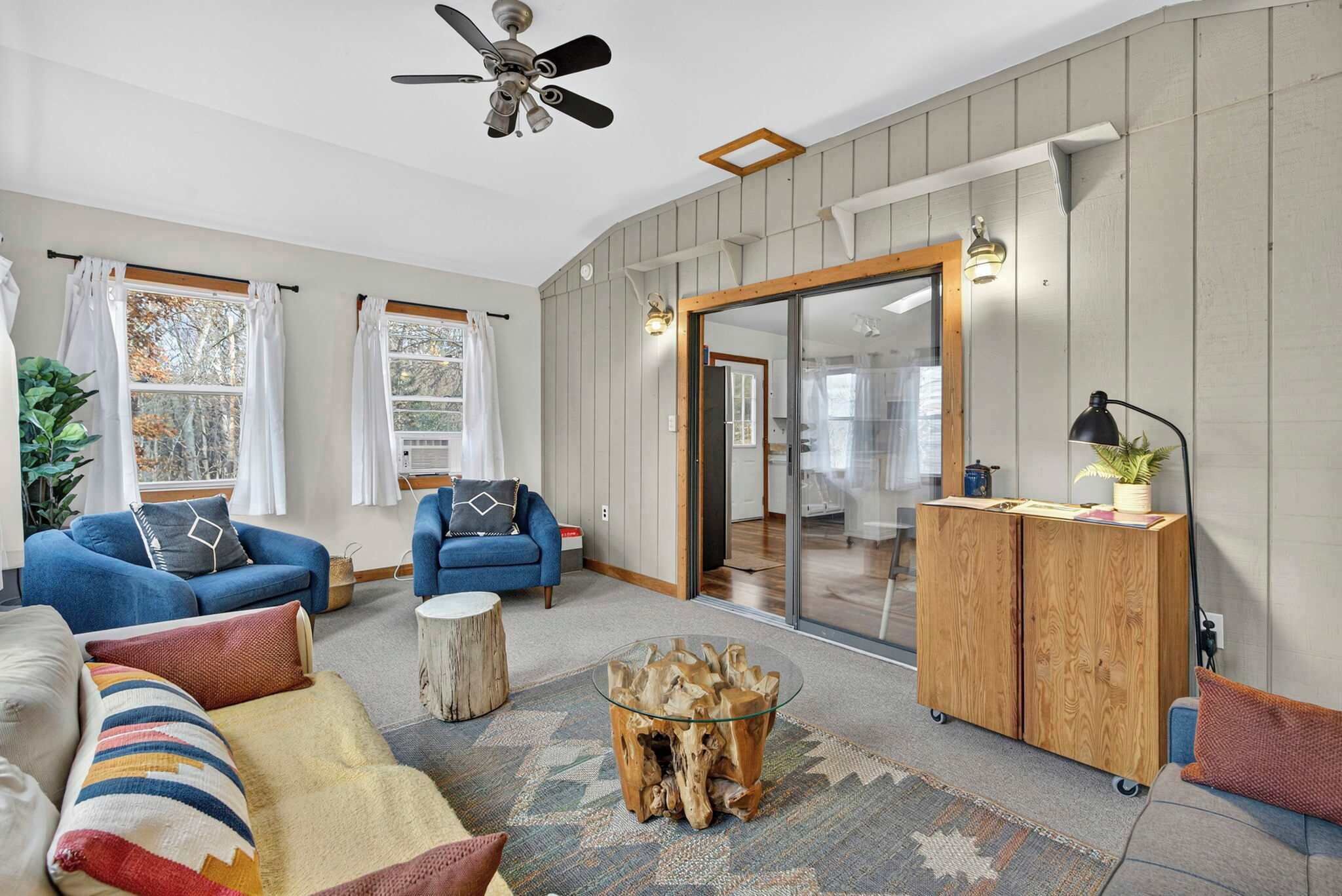 Un salon avec un ventilateur de plafond, deux canapés, une table basse et un meuble.