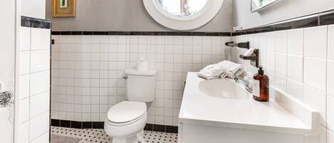 A bathroom with a toilet, sink, and a small window.