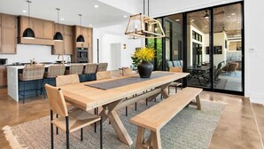 Una cocina moderna con armarios de madera, una isla central y un comedor con una mesa larga y bancos.