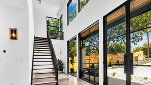 Un interior moderno con una escalera, ventanas amplias y vistas al exterior.