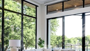 Amplia sala de estar con ventanas grandes, ventilador de techo y un conjunto de sofás modernos.
