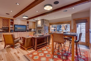 A spacious kitchen with wooden cabinets, a stone accent wall, a large island, and a dining area with bar stools.