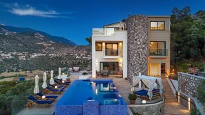 A modern two-story house with a swimming pool, outdoor seating, and a view of the surrounding landscape. - Luxury Villa in Kisla, Kalkan Within Walking Distance to the Beach (Kalkan)