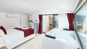 A modern hotel room with a bed, a bathroom with a bathtub, and a sliding glass door leading to a balcony. - Luxury Villa in Kisla, Kalkan Within Walking Distance to the Beach (Kalkan)