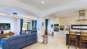 A modern living room with a sofa, a dining area with a table and chairs, and a kitchen with cabinets and appliances. - Luxury Villa in Kisla, Kalkan Within Walking Distance to the Beach (Kalkan)