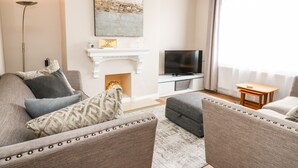 A modern living room with a fireplace, a television, and a cozy seating area. - Welsh Valley House (Ammanford)
