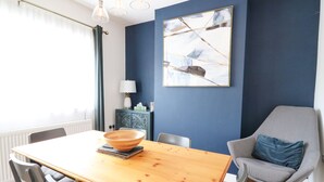 A dining area with a wooden table, chairs, and a blue accent wall. - Welsh Valley House (Ammanford)