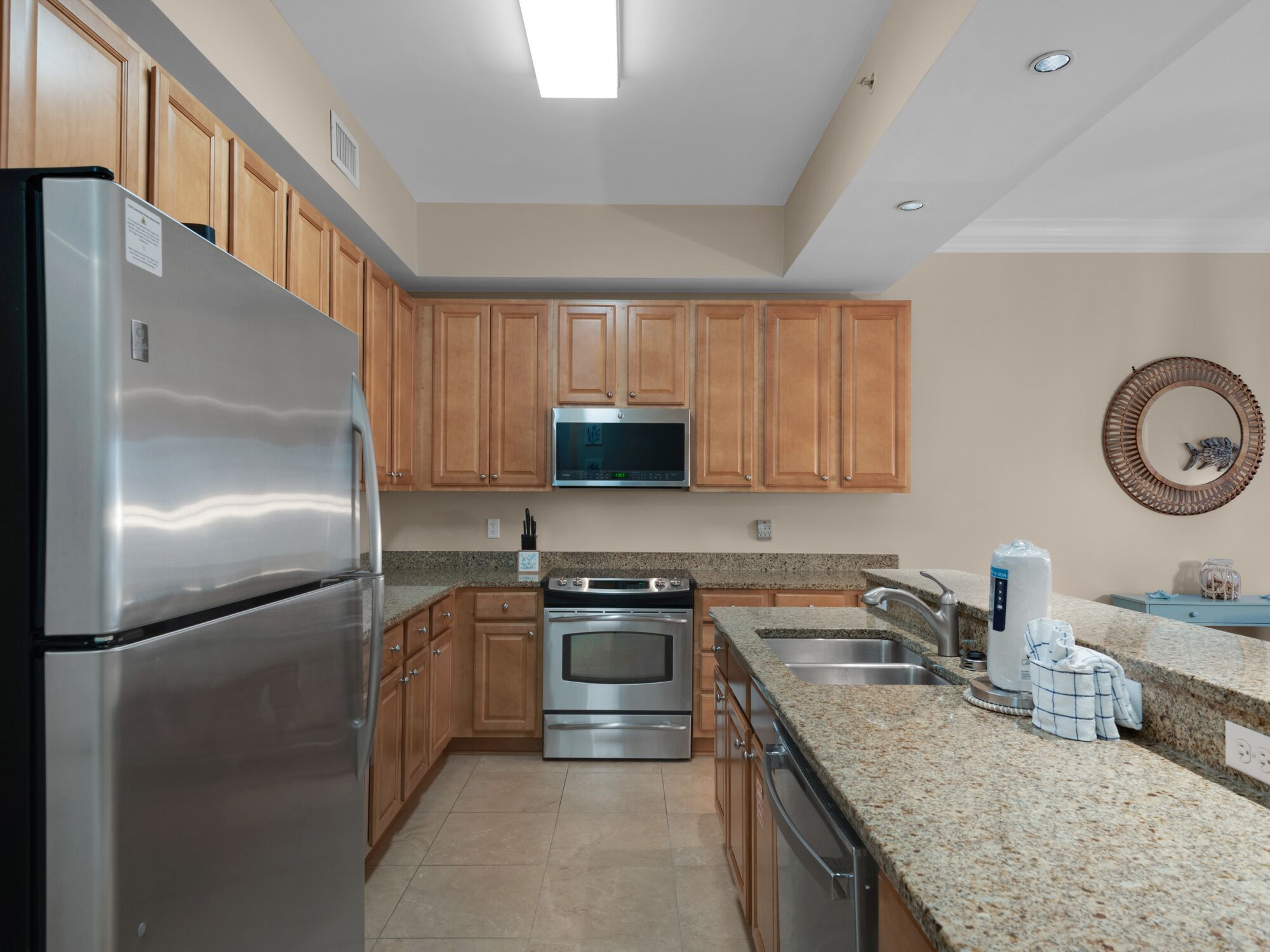 A modern kitchen with wooden cabinets, stainless steel appliances, granite countertops, and a microwave above the stove.