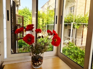 Enjoy a serene view of the lush garden through the window, featuring a beautiful arrangement of flowers on the ledge.