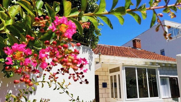 A white building with a tiled roof, a balcony, and a window. - Insideout Apartment (Dubrovnik)