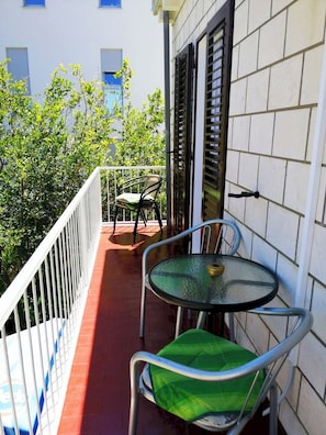 Enjoy a peaceful retreat on this balcony with a round table and comfortable chair.