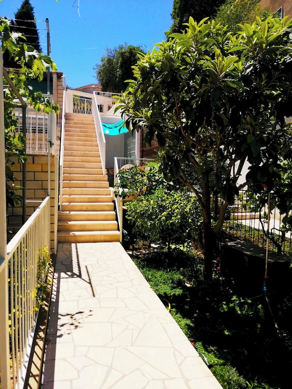 Stairs lead up to a building surrounded by lush greenery and a clear sky.
