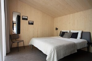 A bedroom with a bed, a chair, and a mirror on a wooden wall. - Buitenplaats Petersburg (Arnhem)