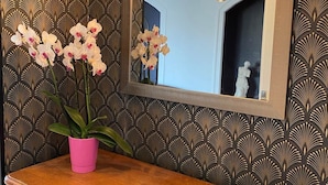 A wooden dresser with a mirror above it, a pink potted plant, and a decorative light fixture. - Rose Room (Saint-Didier-de-la-Tour)