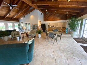 A spacious indoor area with a high ceiling, a dining table with chairs, and a seating area with sofas and armchairs. - Stunning Second Floor Park Shore Resort Unit 223 (Naples)