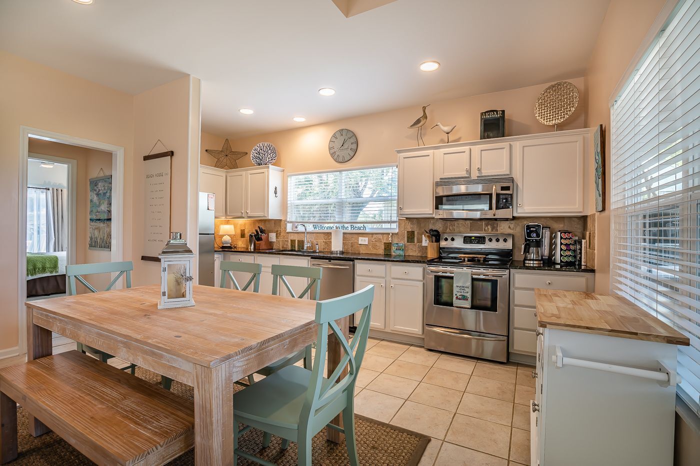 A modern kitchen with white cabinets, stainless steel appliances, and a wooden dining table.