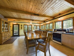 A spacious kitchen with wooden cabinets, a dining table, and large windows. - Spacious UP Retreat with Sauna & Direct Trail Access (Wetmore)
