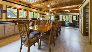 A spacious kitchen with a large dining table, wooden chairs, and a high ceiling with exposed beams. - Spacious UP Retreat with Sauna & Direct Trail Access (Wetmore)