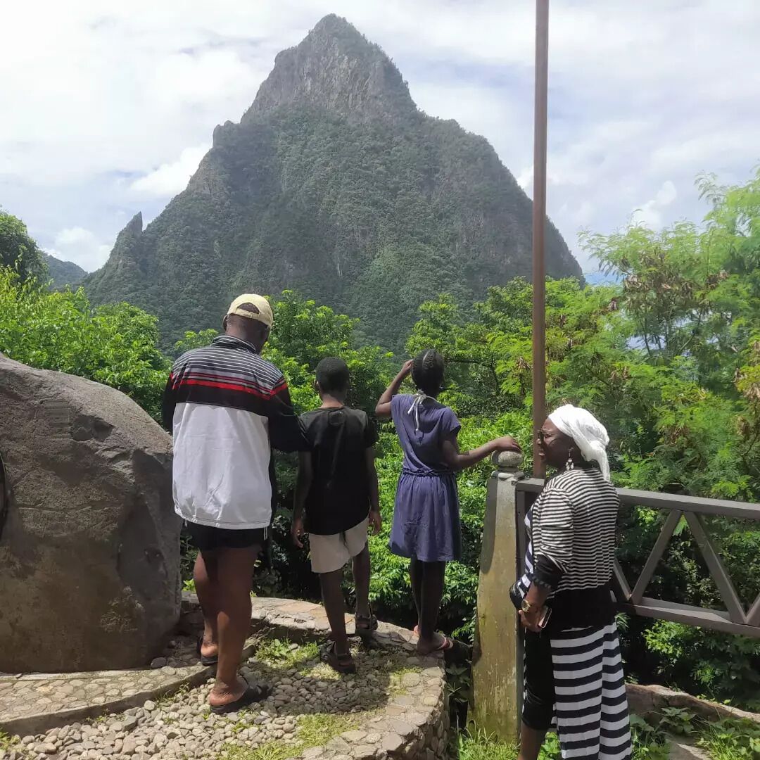 A group of people standing on a stone pathway with a view of a mountain.