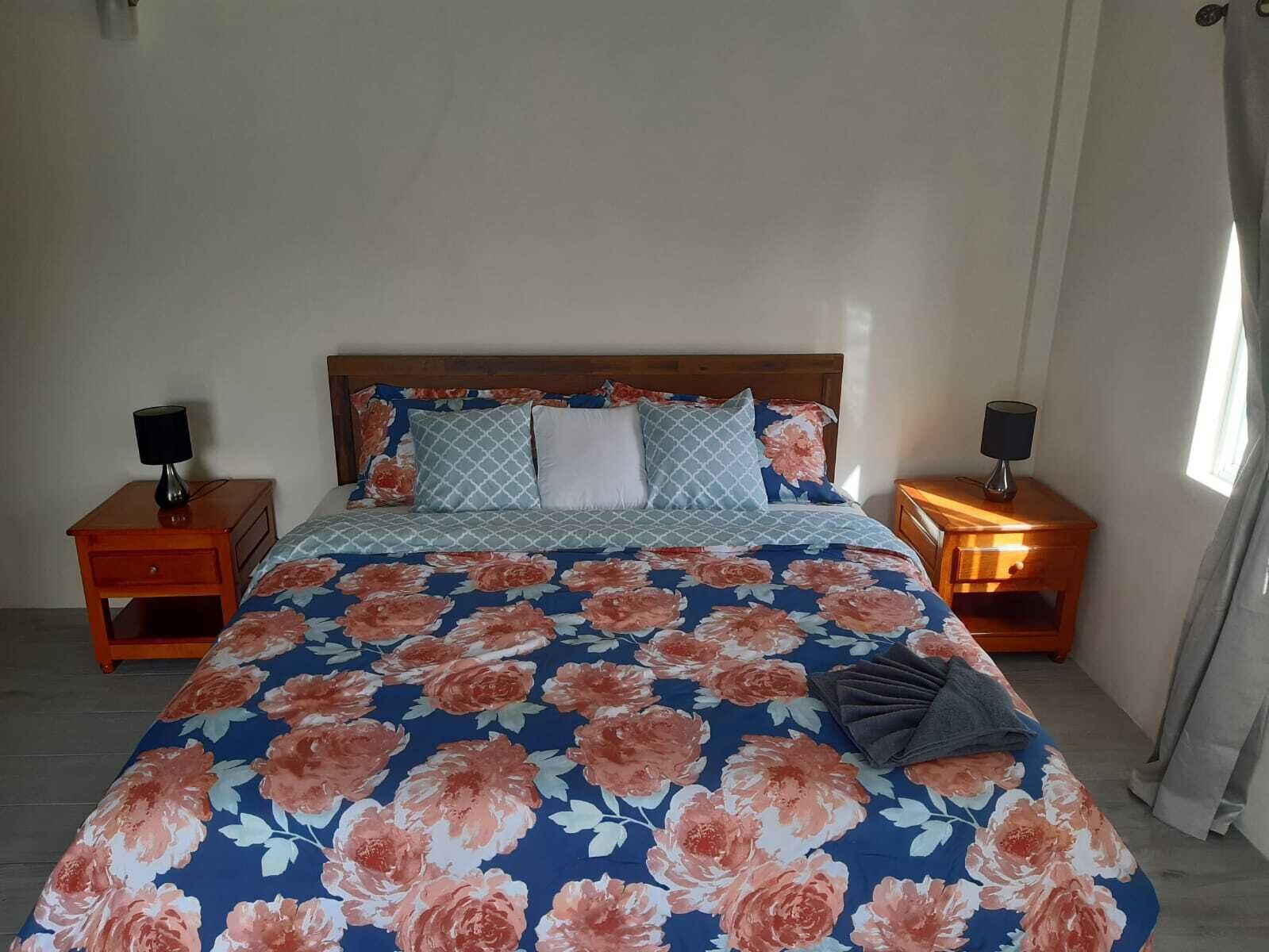 A bedroom with a bed, two nightstands, and a window with curtains.
