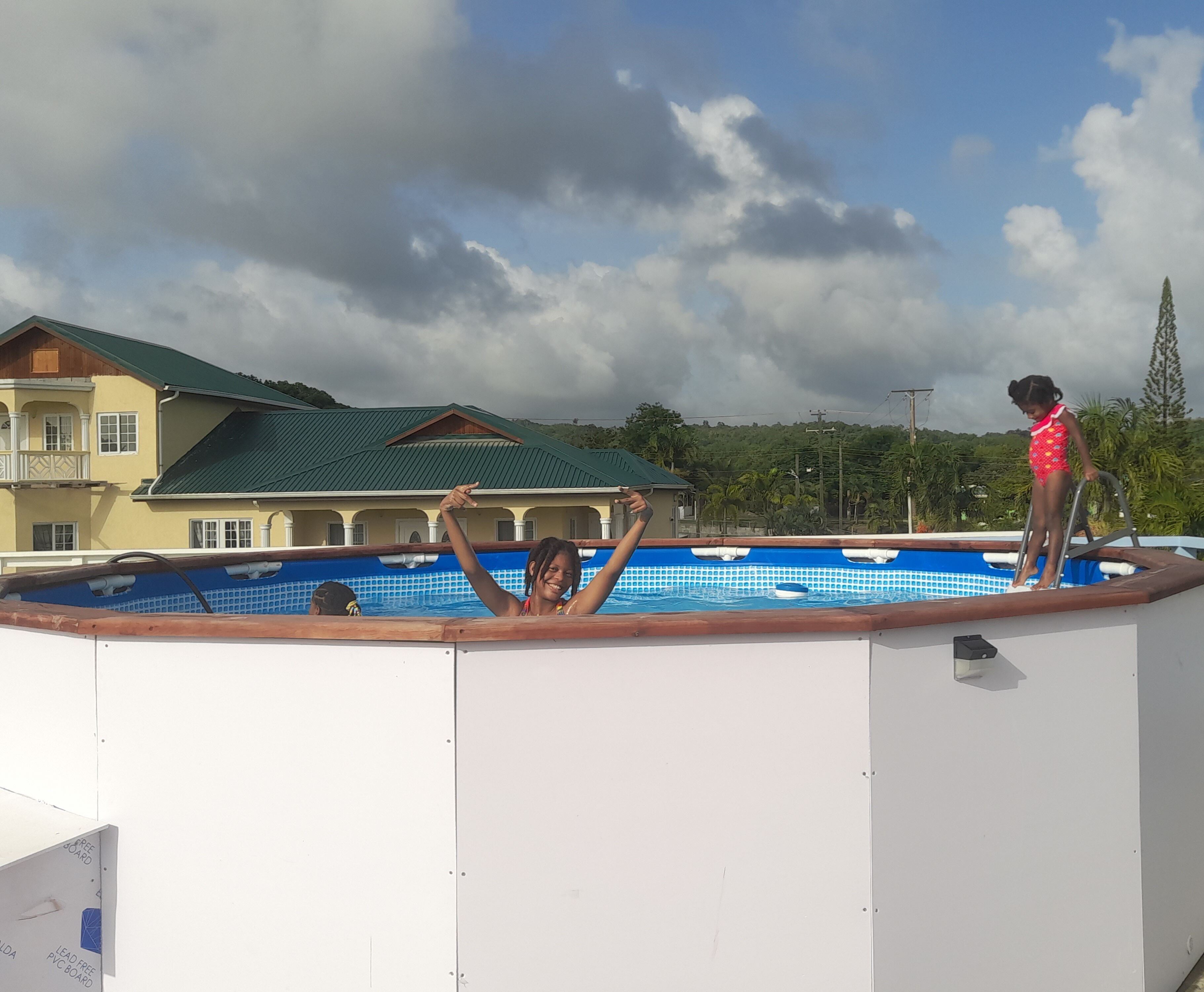 A swimming pool with a view of a house and trees in the background.