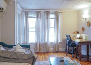 A room with a bed, a desk, a chair, and a window with curtains.